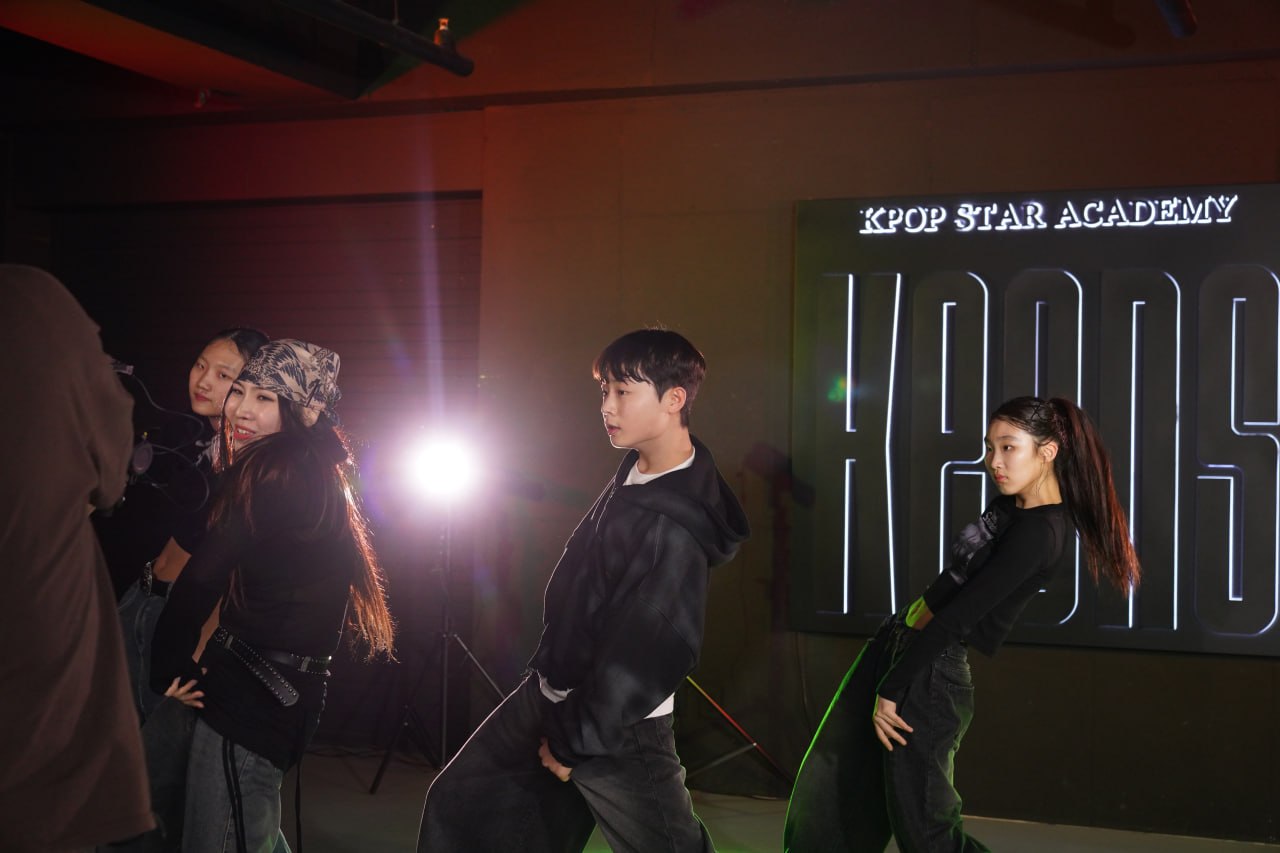 Keens Academy trainees mid-choreography under the KEENS LED sign